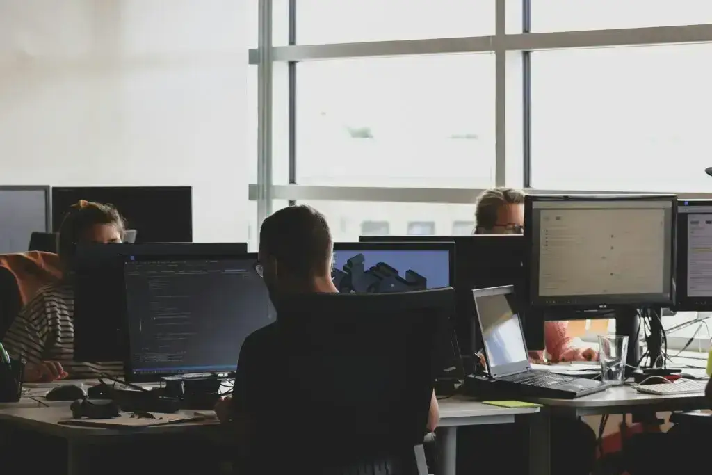 row of desktop computers with cables on desk